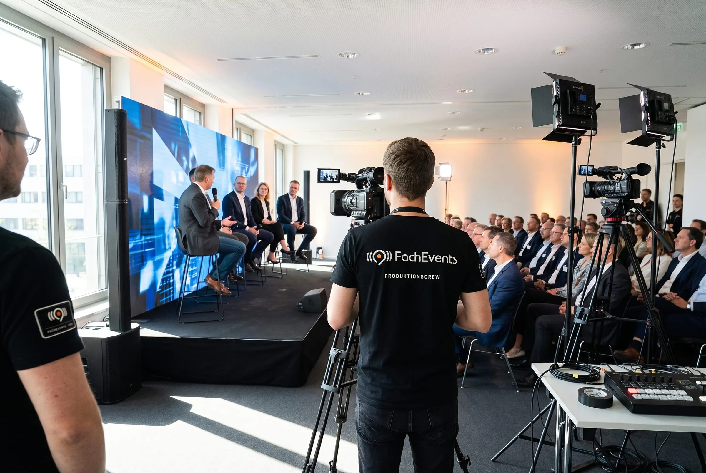 Fachtagung eines Verbands: Podiumsdiskussion vor der LED-Wand, vorn Kameramann und Regieplatz