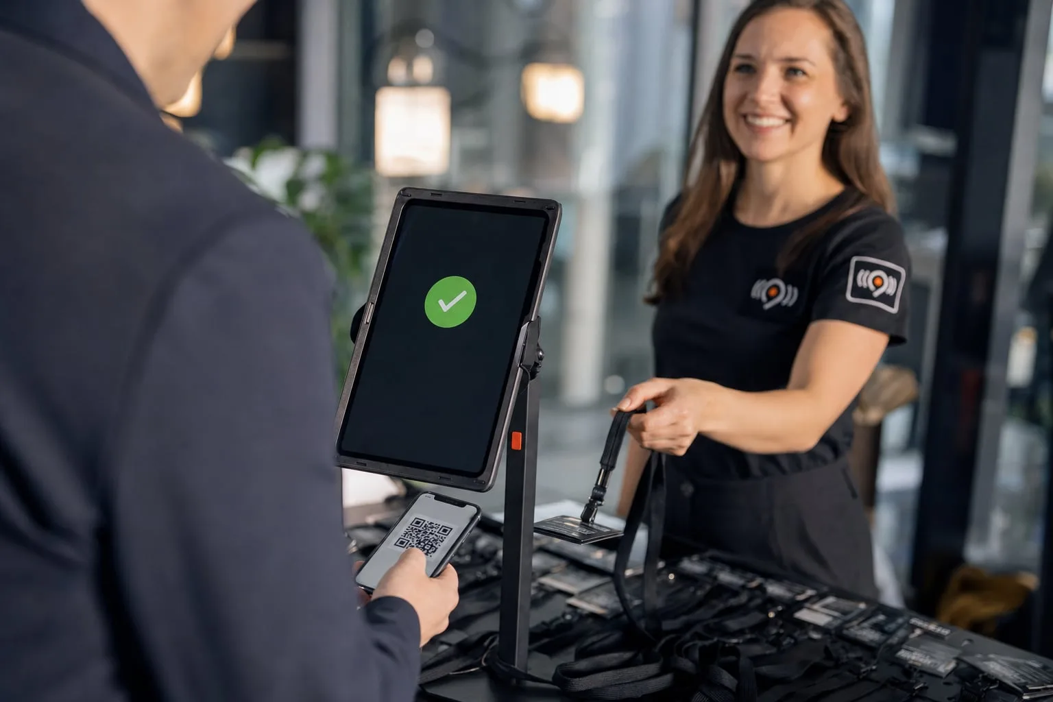 Check-in per QR-Code: Ein Gast scannt sein Ticket am Tablet, am Empfang liegen die Namensschilder bereit