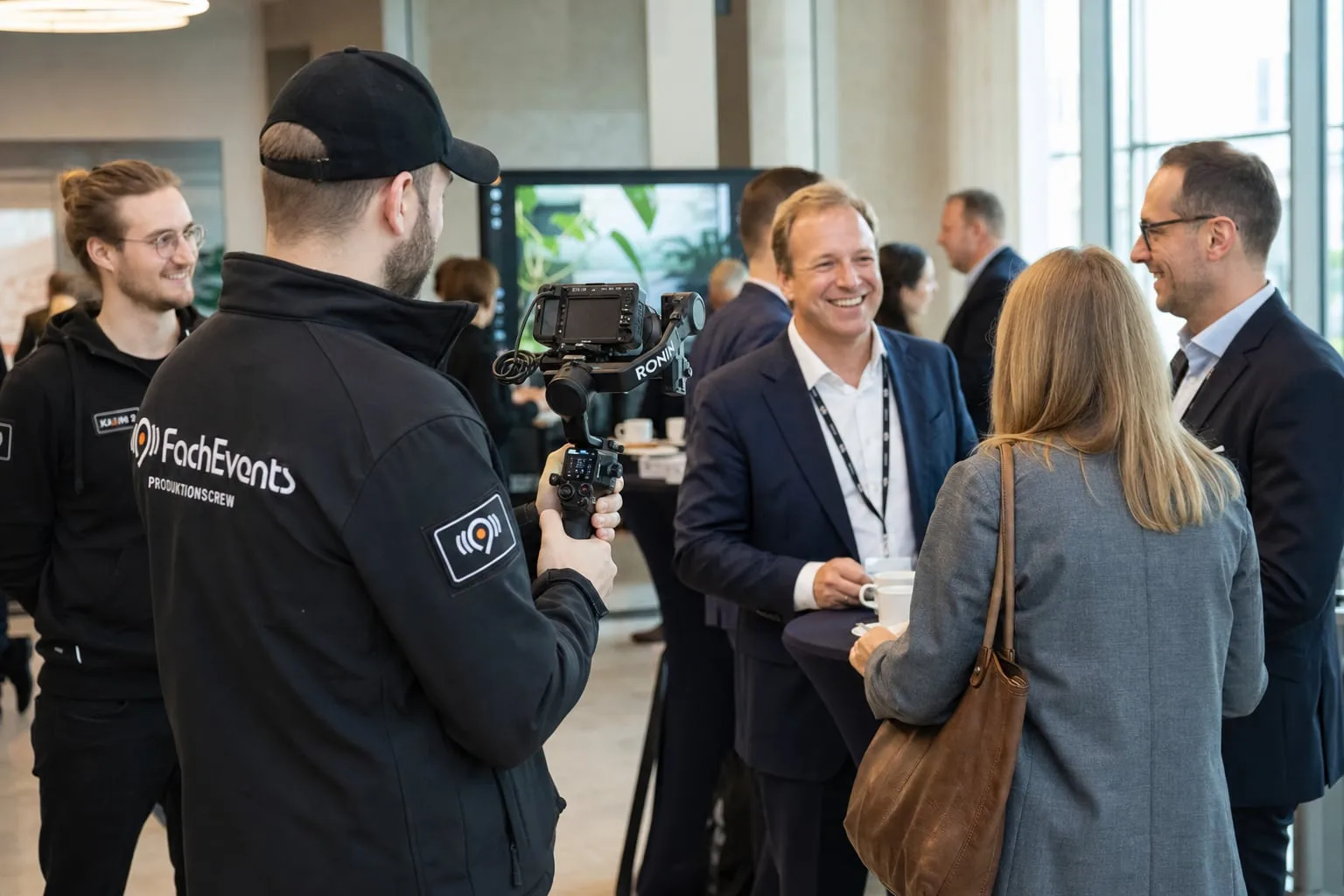 Eventfilm: Ein Videograf filmt Gäste beim Gespräch in der Kaffeepause mit einer Gimbal-Kamera