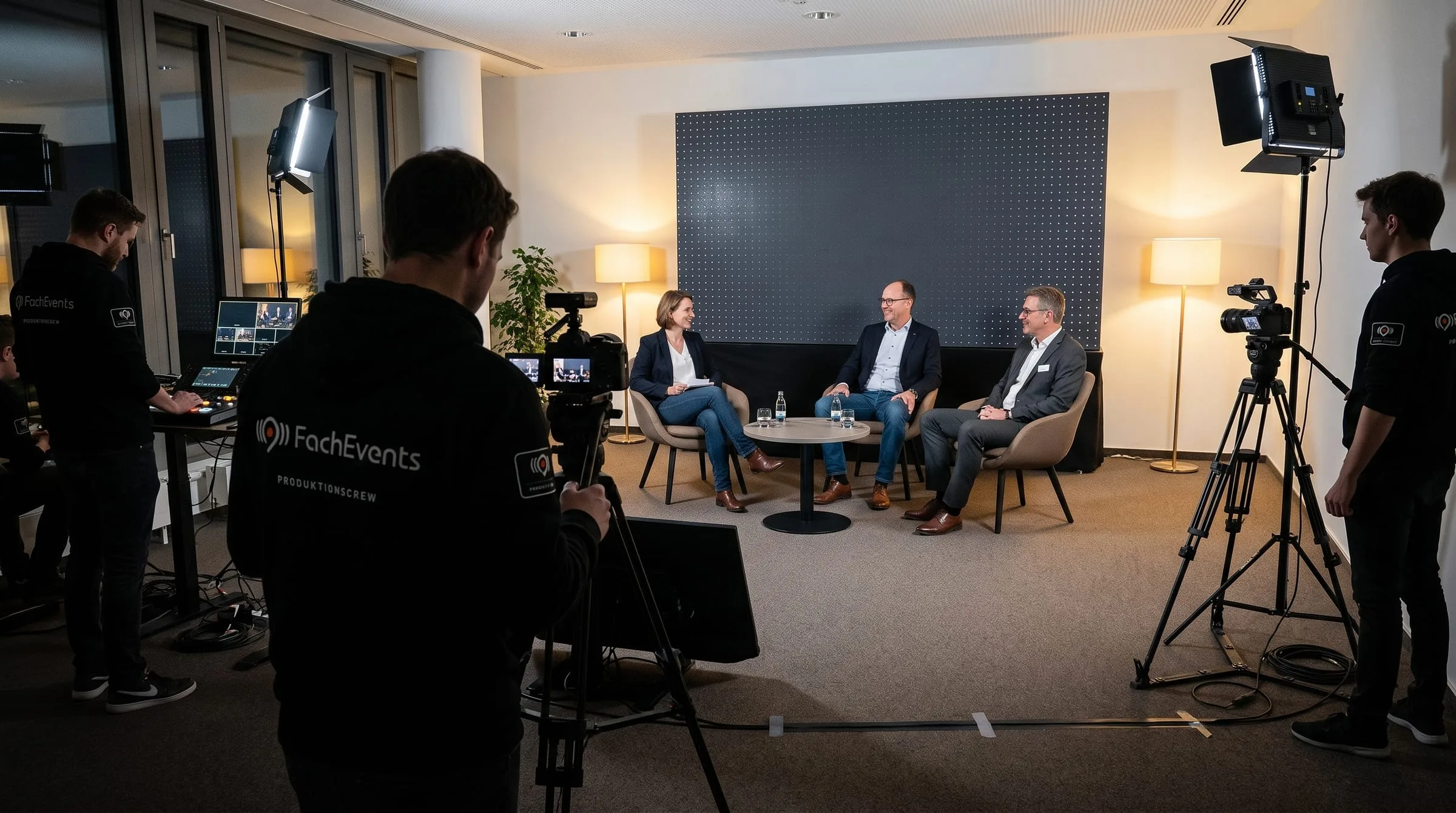 Expertenrunde vor der LED-Wand, vorn ein Kameramann, links der Regieplatz